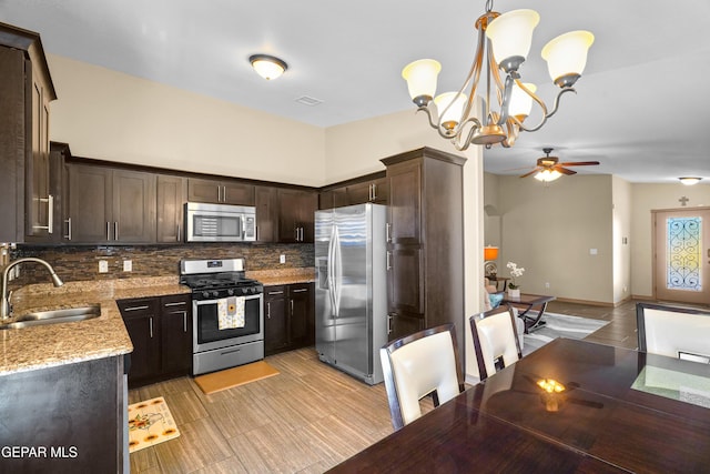 kitchen with decorative light fixtures, sink, dark brown cabinetry, light stone countertops, and stainless steel appliances