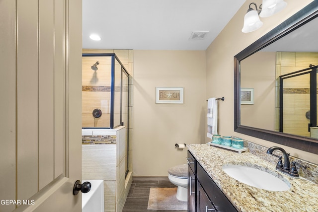 bathroom featuring toilet, vanity, and a shower with door