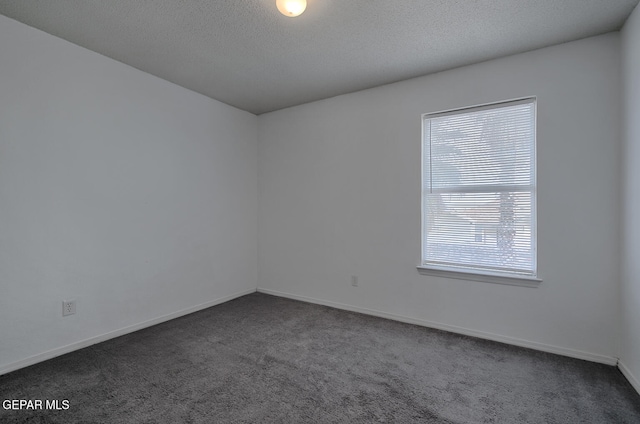 empty room featuring a textured ceiling and dark colored carpet