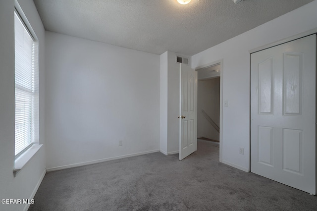 unfurnished bedroom with carpet, a textured ceiling, and a closet