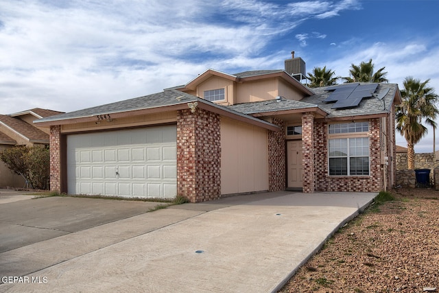 view of front of home with central air condition unit, a garage, and solar panels