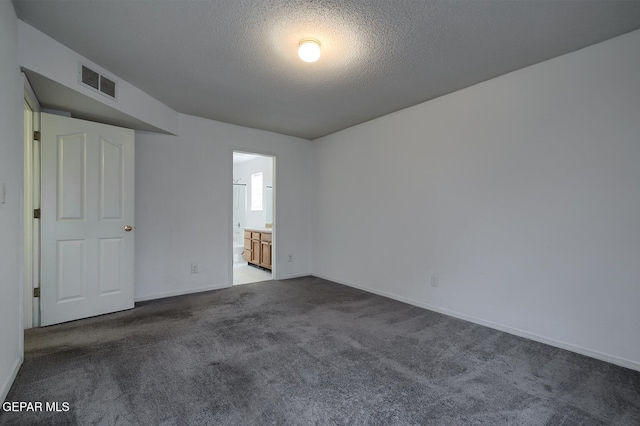 unfurnished room with dark carpet and a textured ceiling