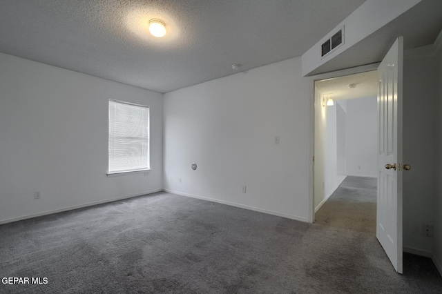 spare room with dark carpet and a textured ceiling