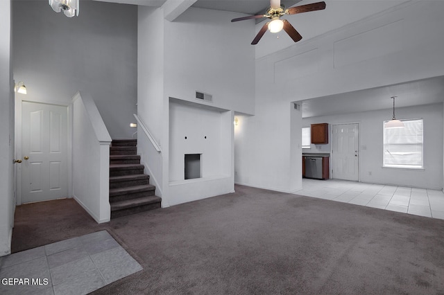 unfurnished living room with ceiling fan, a towering ceiling, and light carpet