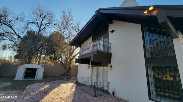 view of side of home featuring a balcony and a storage unit