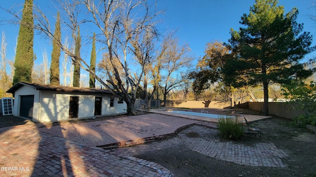 view of pool with a garage, an outdoor structure, and a patio area