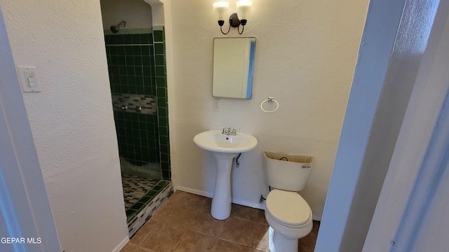 bathroom with tile patterned flooring, toilet, and tiled shower