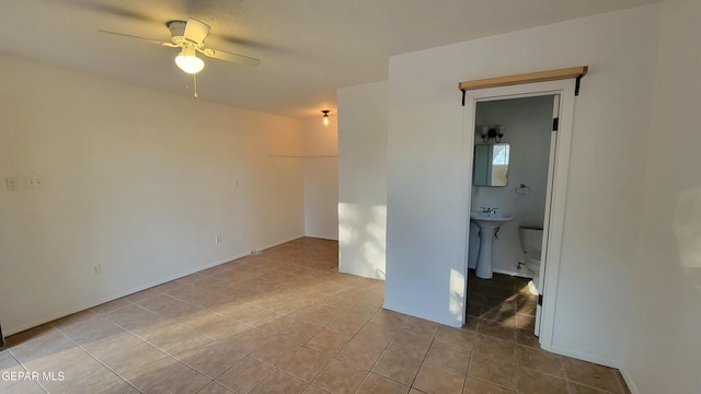 tiled empty room with ceiling fan and sink