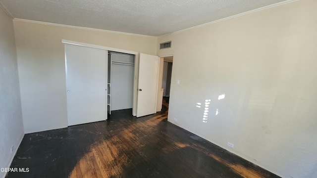 unfurnished bedroom with crown molding, dark wood-type flooring, and a closet