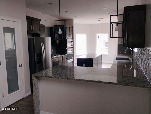 kitchen featuring a center island, sink, appliances with stainless steel finishes, decorative light fixtures, and kitchen peninsula