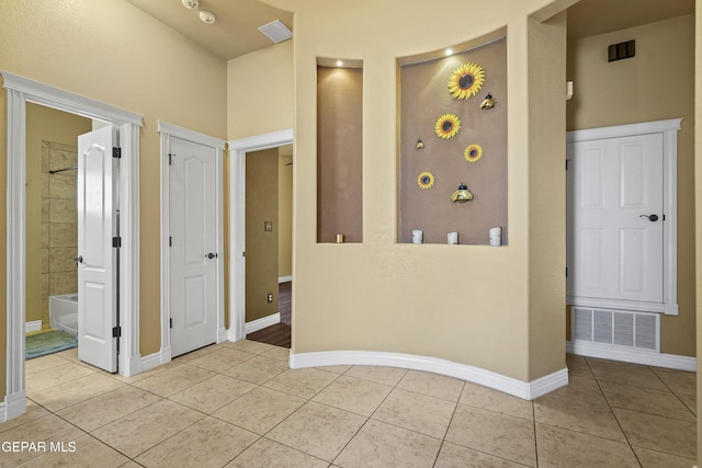 empty room featuring light tile patterned flooring, baseboards, and visible vents