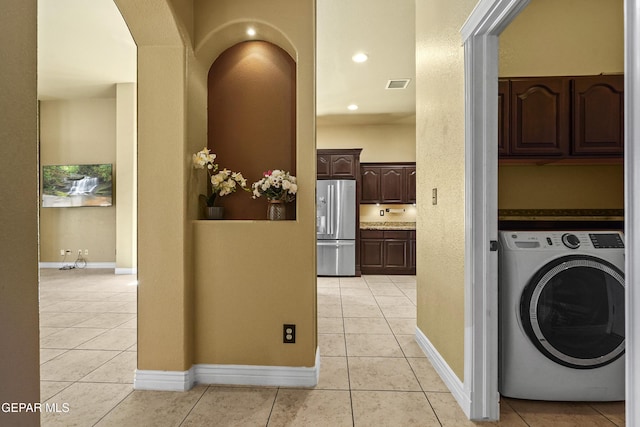 clothes washing area with light tile patterned floors, visible vents, cabinet space, and washer / dryer