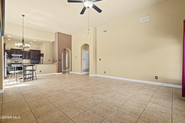 unfurnished living room with visible vents, arched walkways, baseboards, and ceiling fan with notable chandelier