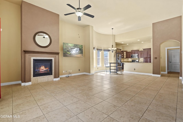 unfurnished living room with light tile patterned floors, a tile fireplace, a ceiling fan, and baseboards