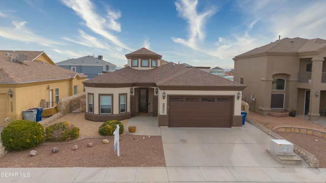 view of front facade featuring stucco siding, an attached garage, concrete driveway, and roof with shingles