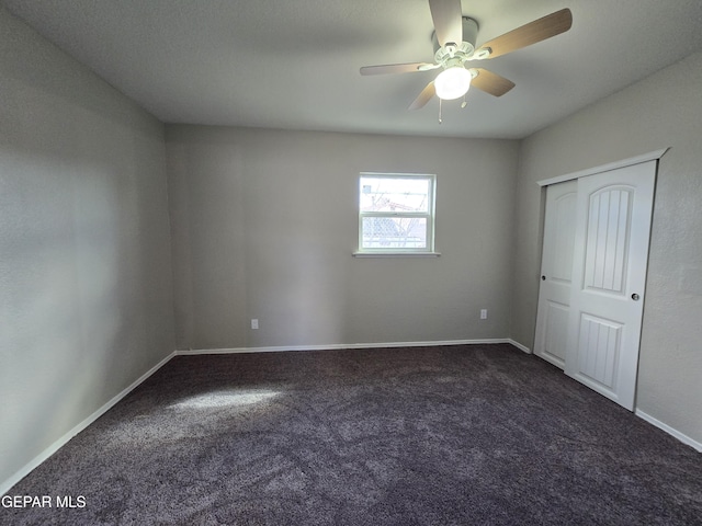 unfurnished bedroom with dark carpet and ceiling fan