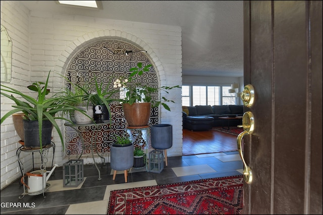 interior space with brick wall and a textured ceiling