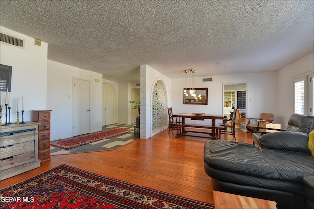 living room featuring a textured ceiling, a notable chandelier, and hardwood / wood-style flooring