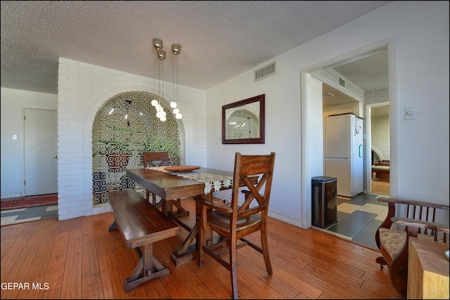 dining space featuring a textured ceiling and hardwood / wood-style floors