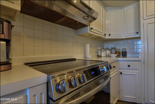 kitchen featuring premium range hood, electric stove, tasteful backsplash, and white cabinetry