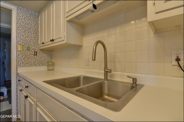 kitchen with white cabinets, backsplash, and sink