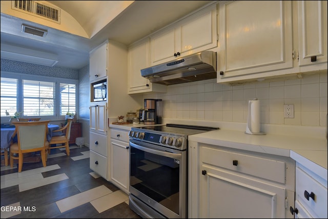 kitchen featuring stainless steel electric stove, white cabinetry, and backsplash