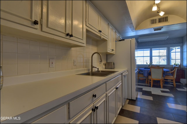 kitchen featuring sink, dishwasher, vaulted ceiling, and backsplash