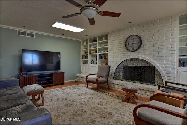 living room featuring wood-type flooring, ceiling fan, ornamental molding, a fireplace, and built in shelves