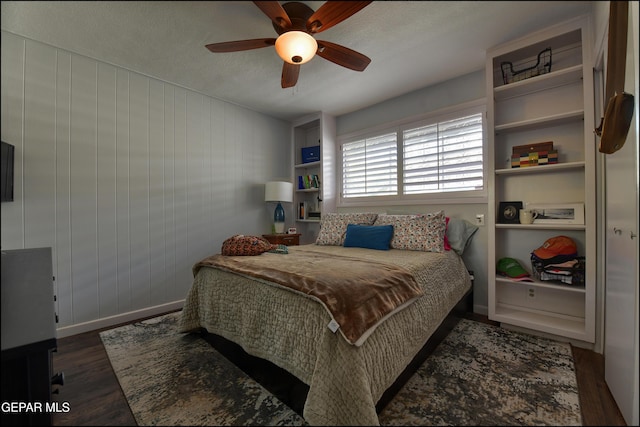 bedroom featuring wood walls, ceiling fan, a textured ceiling, and dark hardwood / wood-style floors