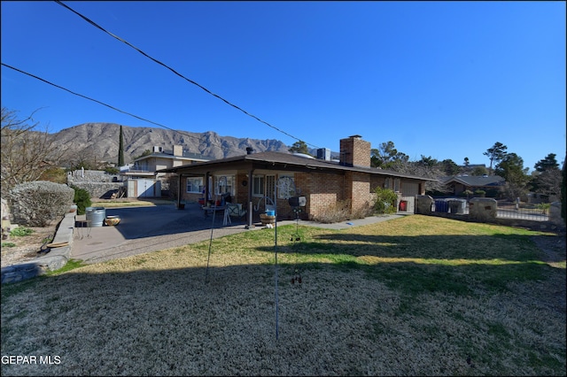 rear view of property with a patio, a yard, and a mountain view