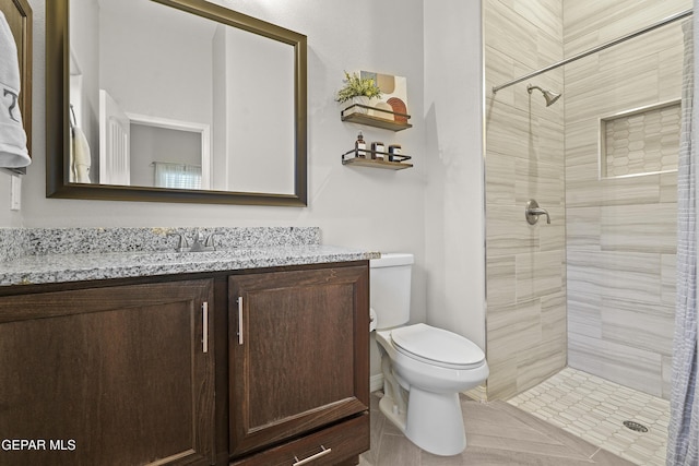 bathroom featuring vanity, toilet, and a tile shower