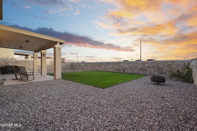 yard at dusk featuring a patio and an outdoor fire pit