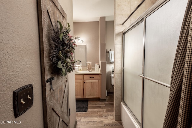 bathroom with vanity, hardwood / wood-style floors, and bath / shower combo with glass door