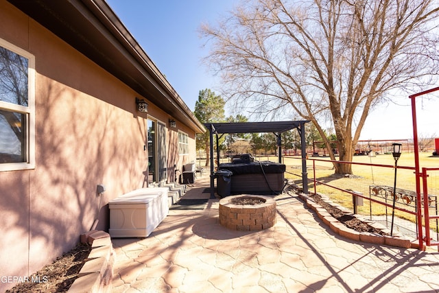 view of patio / terrace with a hot tub, a pergola, and an outdoor fire pit