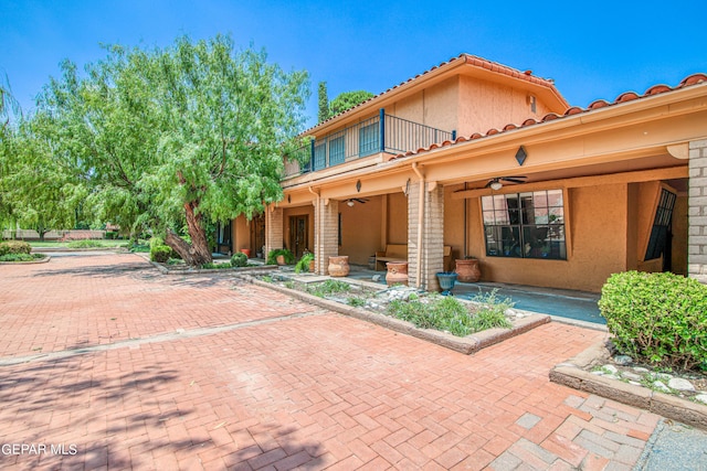 exterior space with covered porch, ceiling fan, and a balcony