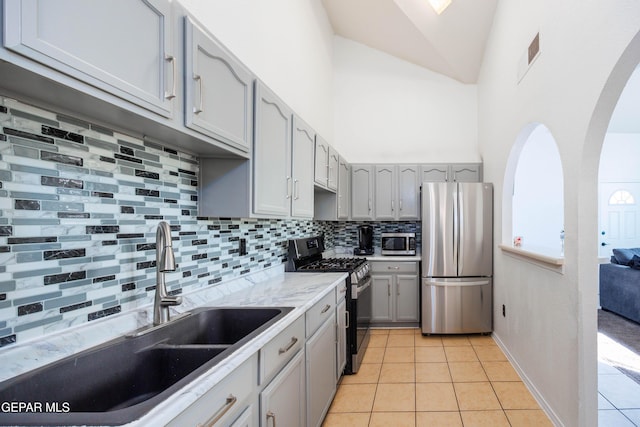 kitchen featuring gray cabinetry, sink, stainless steel appliances, decorative backsplash, and light tile patterned flooring