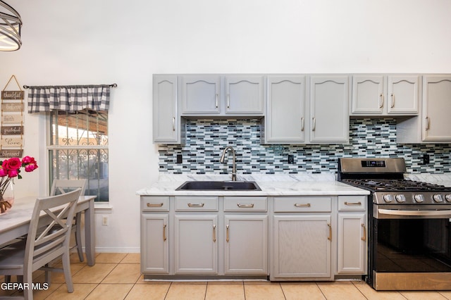 kitchen with light stone countertops, sink, stainless steel gas range oven, decorative backsplash, and light tile patterned floors