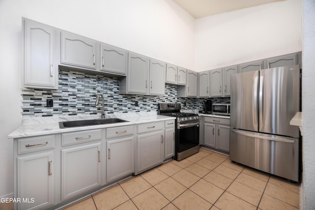 kitchen featuring decorative backsplash, gray cabinetry, stainless steel appliances, sink, and light tile patterned flooring