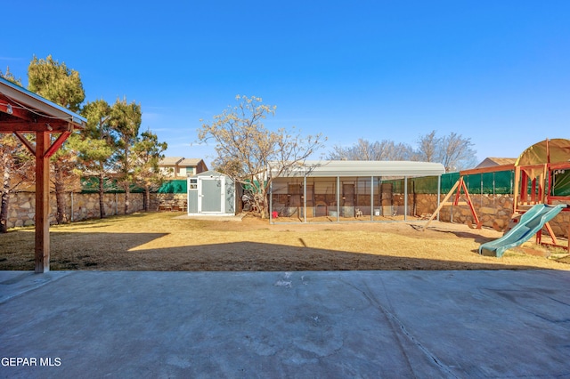 view of yard with a storage shed and a playground