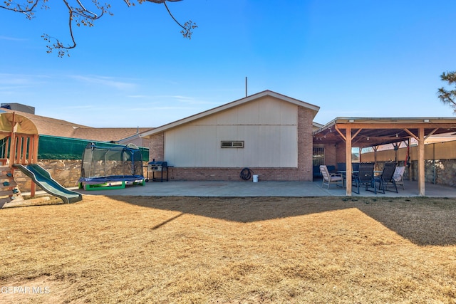 back of house with a playground, a patio area, a trampoline, and a lawn