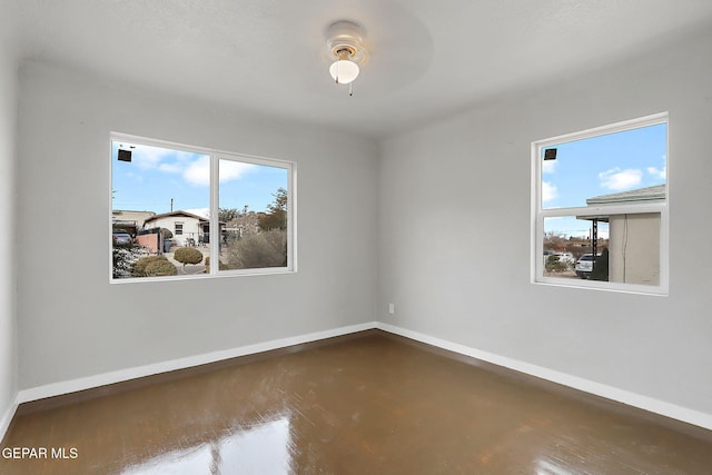 empty room with ceiling fan and a healthy amount of sunlight