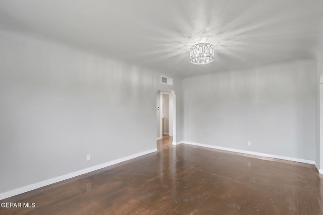 unfurnished room featuring dark wood-type flooring and a chandelier