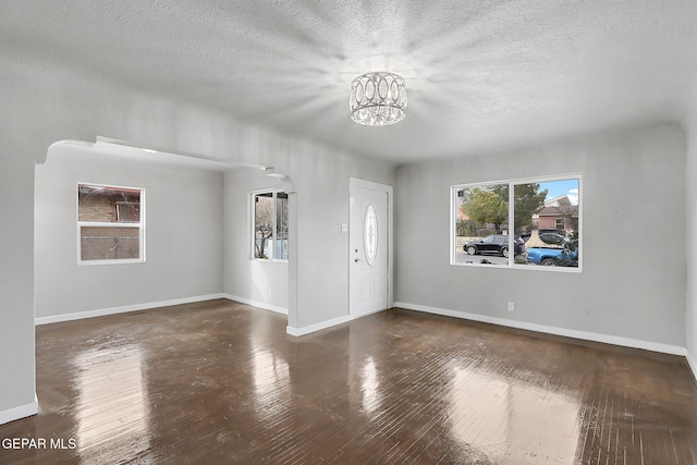 interior space featuring a textured ceiling, dark hardwood / wood-style flooring, and a notable chandelier