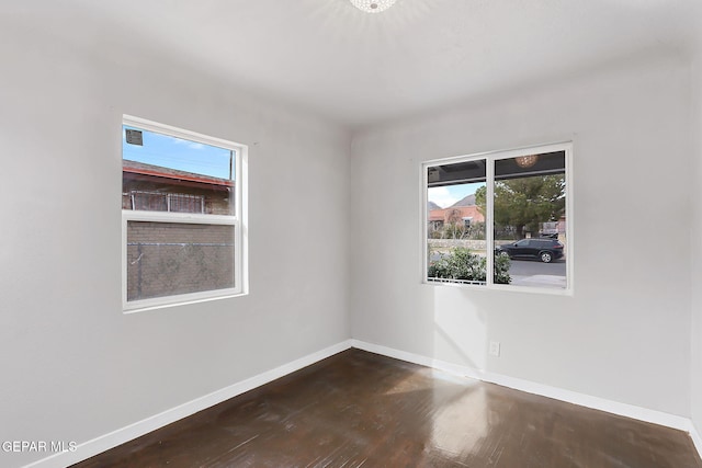 empty room featuring plenty of natural light and dark wood-type flooring