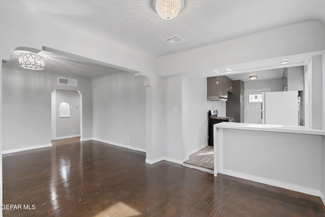 empty room with dark wood-type flooring and a chandelier