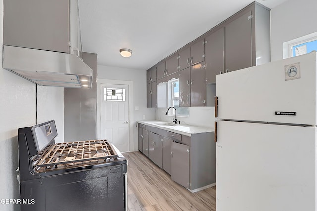 kitchen with light wood-type flooring, black gas range oven, exhaust hood, sink, and white refrigerator