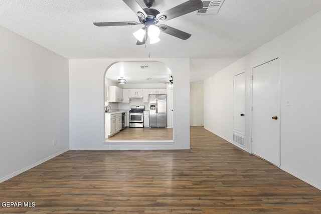 unfurnished living room featuring a textured ceiling, dark hardwood / wood-style floors, and ceiling fan