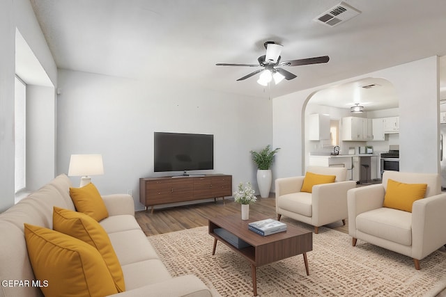 living room featuring ceiling fan, light hardwood / wood-style floors, and a healthy amount of sunlight