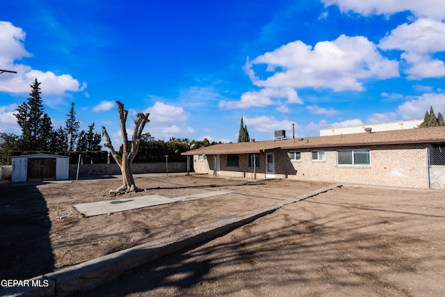 view of front of property with a patio and a storage shed