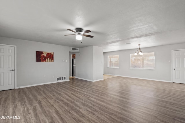 unfurnished living room featuring ceiling fan with notable chandelier, a textured ceiling, and wood-type flooring